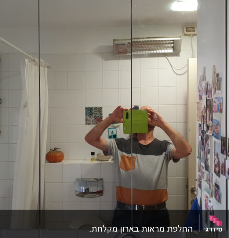 מראה גדולה בחדר אמבטיה עם תמונות על הקיר